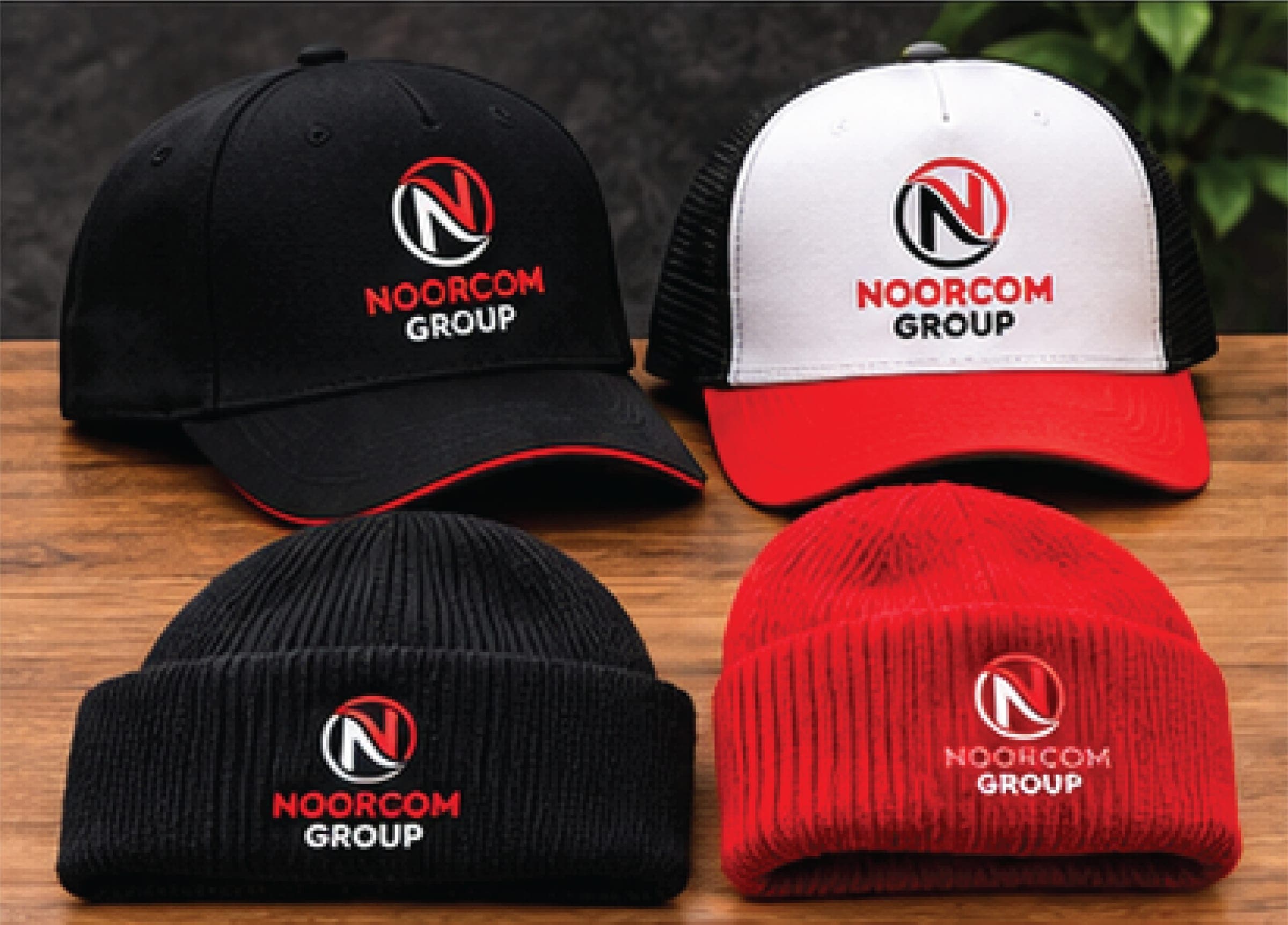 Black and red caps and beanies with the Noorcom Group logo