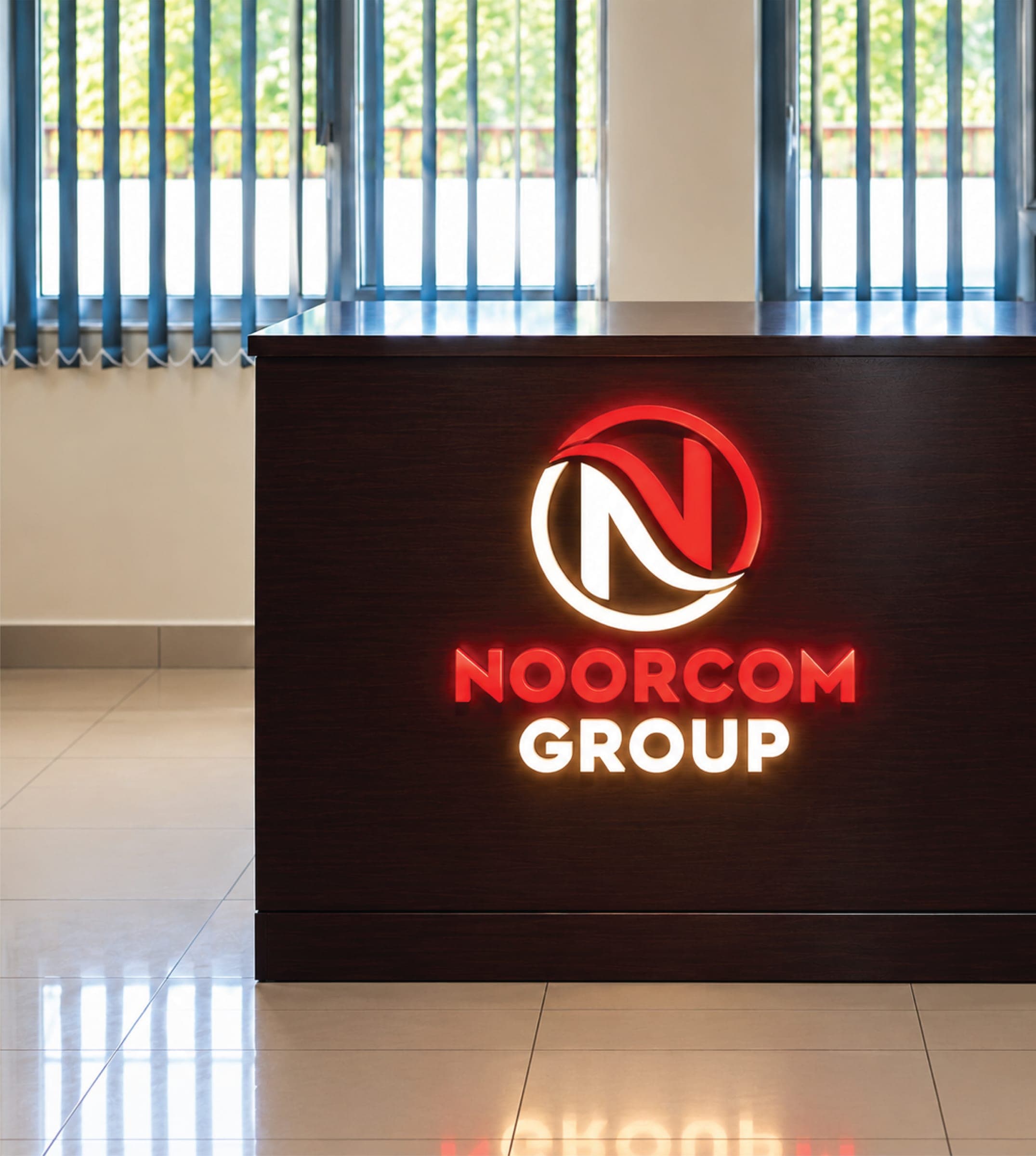 A reception desk with a lit Noorcom Group logo sign