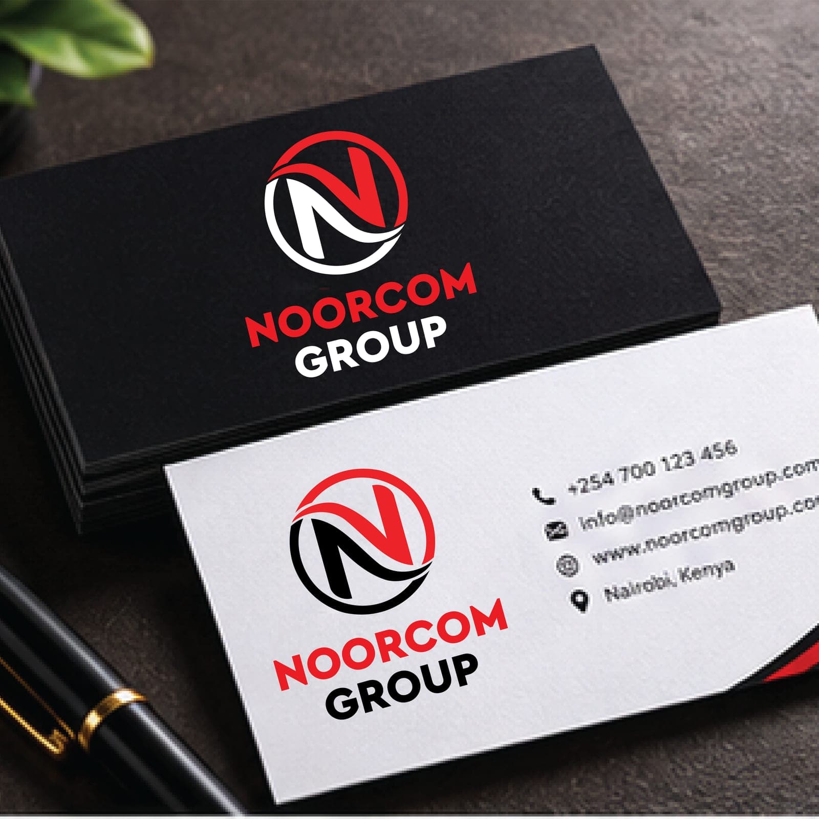 Black and white business cards with the Noorcom Group logo, beside a pen