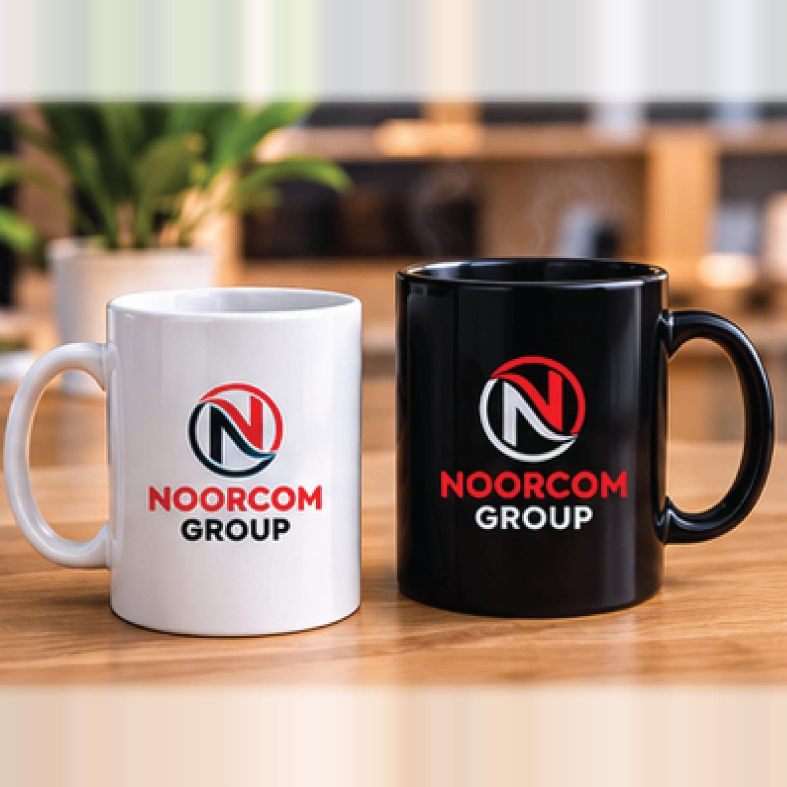 A white mug and a black mug printed with the Noorcom Group logo