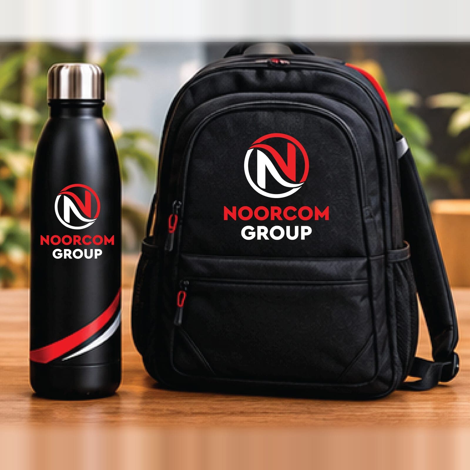 A black water bottle and backpack, both branded with the Noorcom Group logo