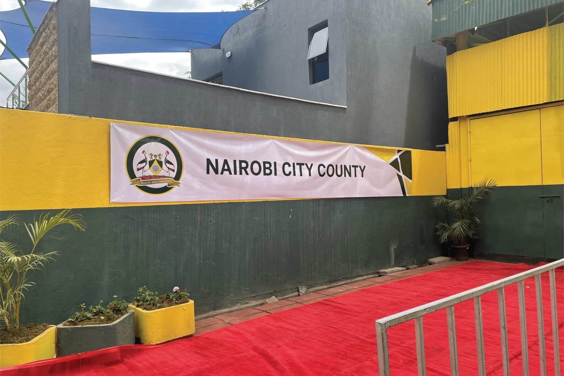 A Nairobi City County banner on a yellow and green wall above a red carpet