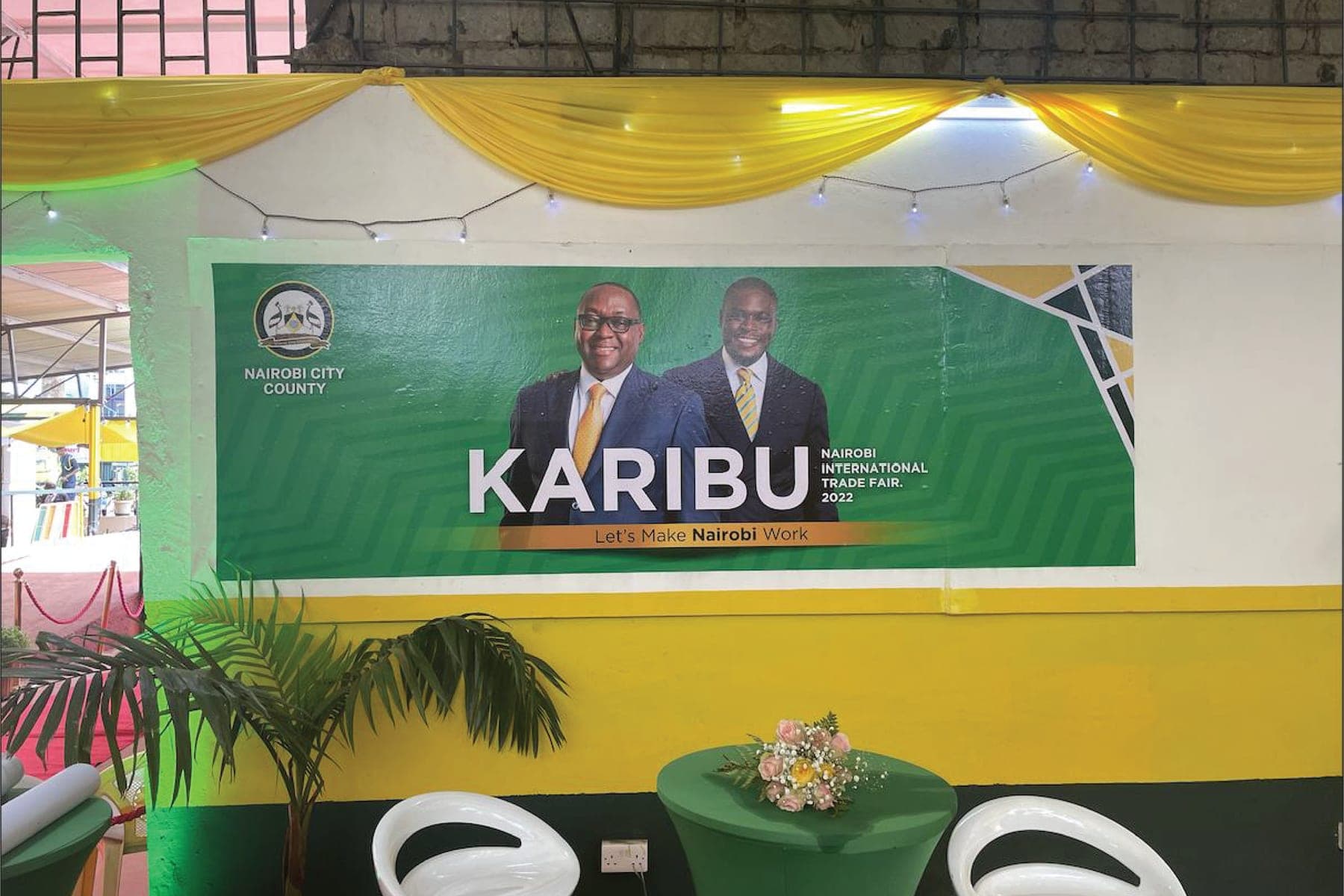 A Karibu, Nairobi International Trade Fair 2022 banner on the stand’s wall, above green tables